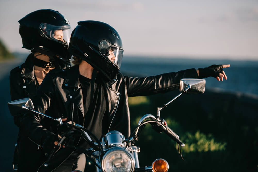 A man and a woman are riding a motorcycle on a road.