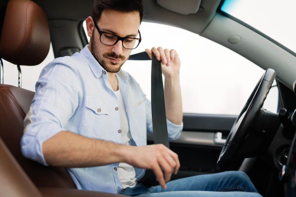 A man is putting on his seat belt in a car.