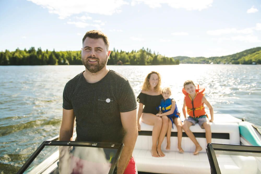 A man is standing next to a boat with a family on it.
