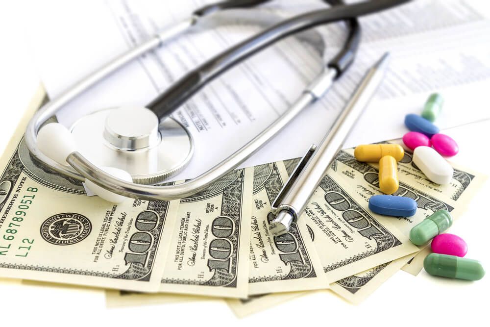A stethoscope is laying on top of a pile of 100 dollar bills
