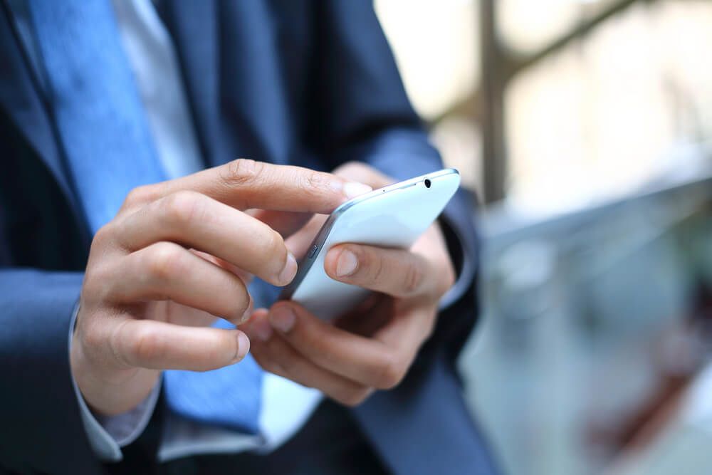 A man in a suit and tie is using a cell phone.