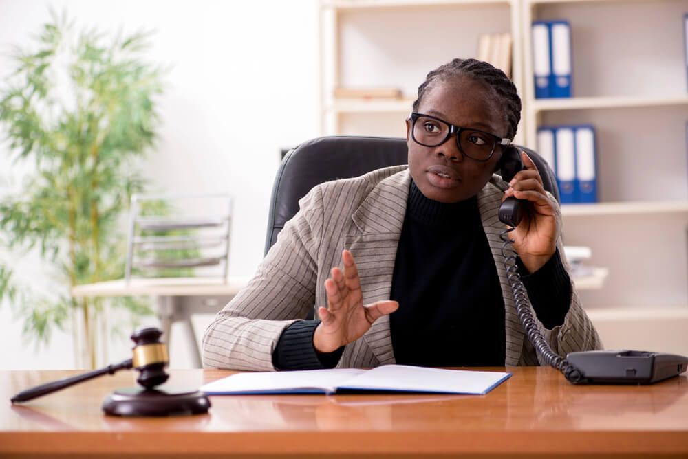 A woman is sitting at a desk talking on a phone.