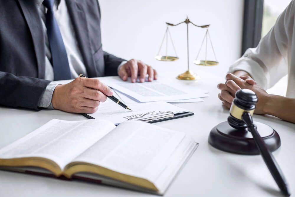 A man and a woman are sitting at a table with a book and a gavel.