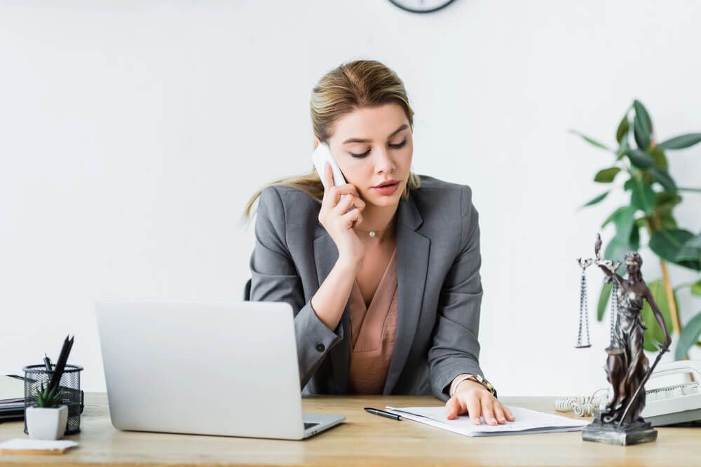 A woman is sitting at a desk talking on a cell phone.