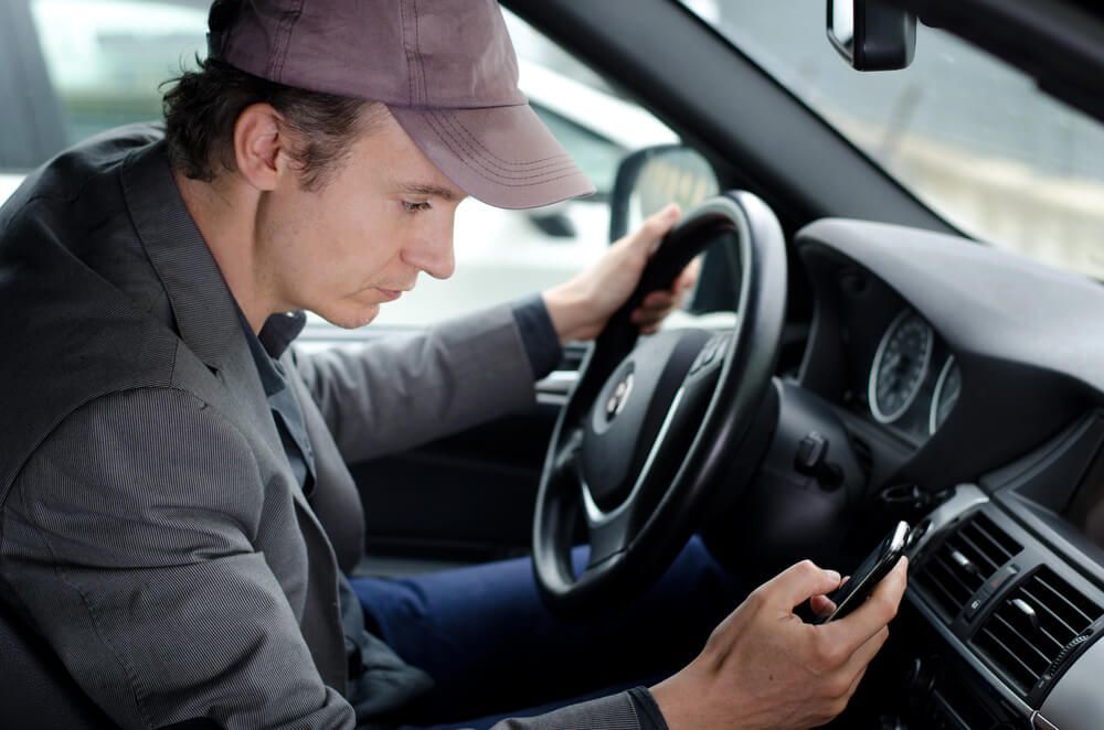 A man is sitting in a car looking at his phone