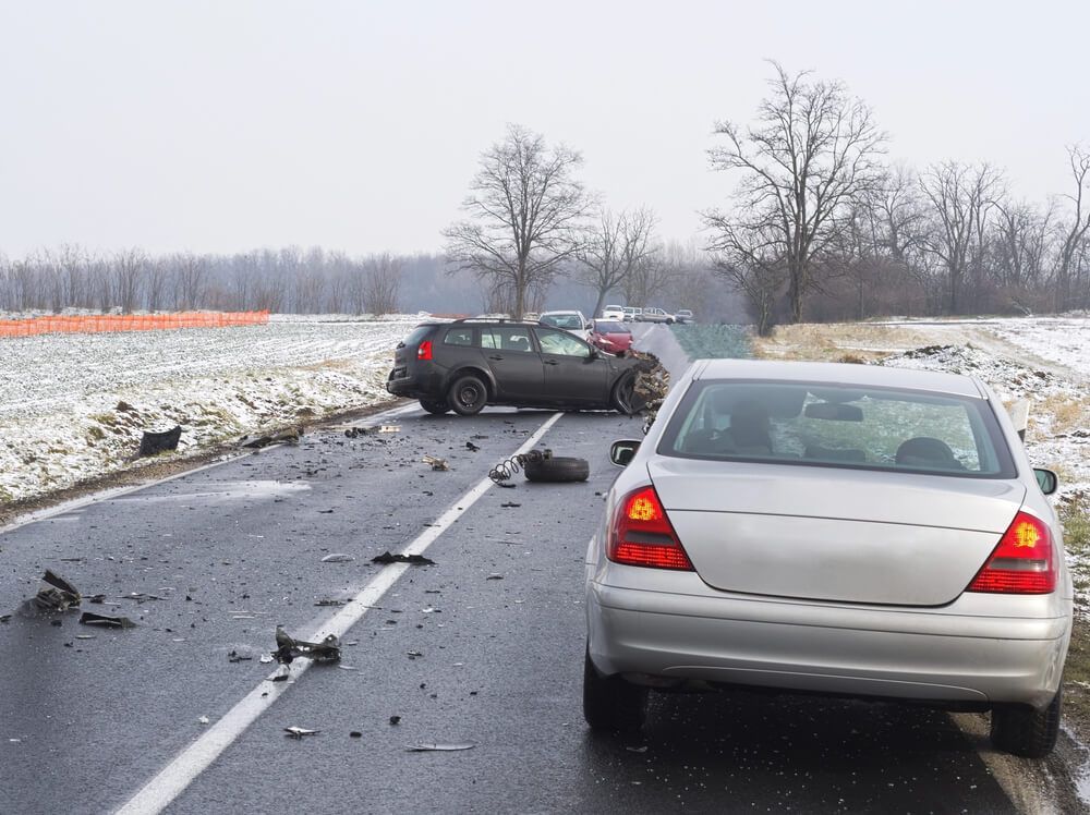 A white car is parked on the side of a snowy road