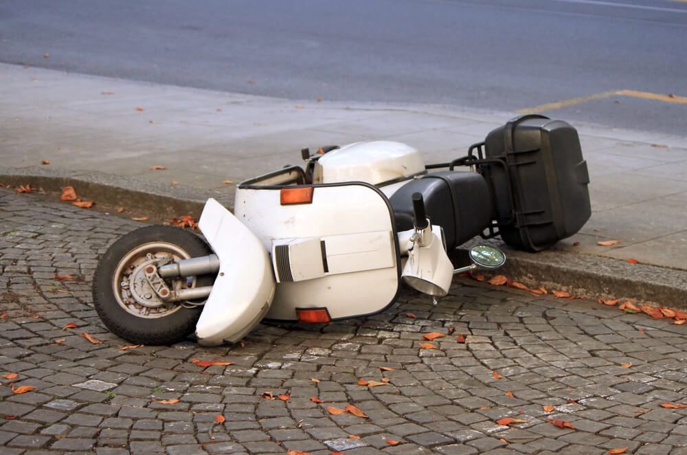 A motorcycle is laying on its side on the sidewalk.