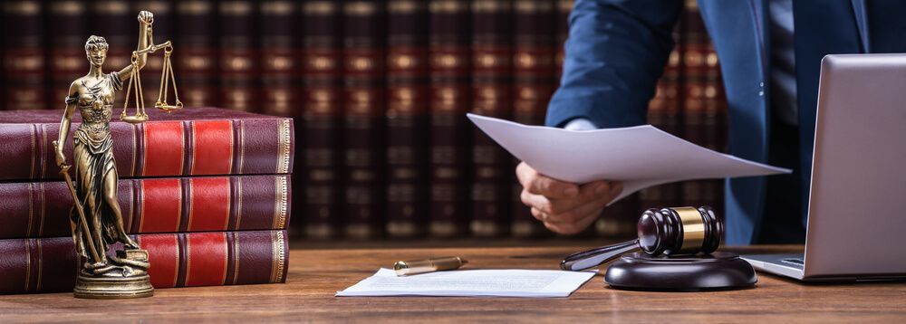 A lawyer is holding a piece of paper in front of a laptop computer.
