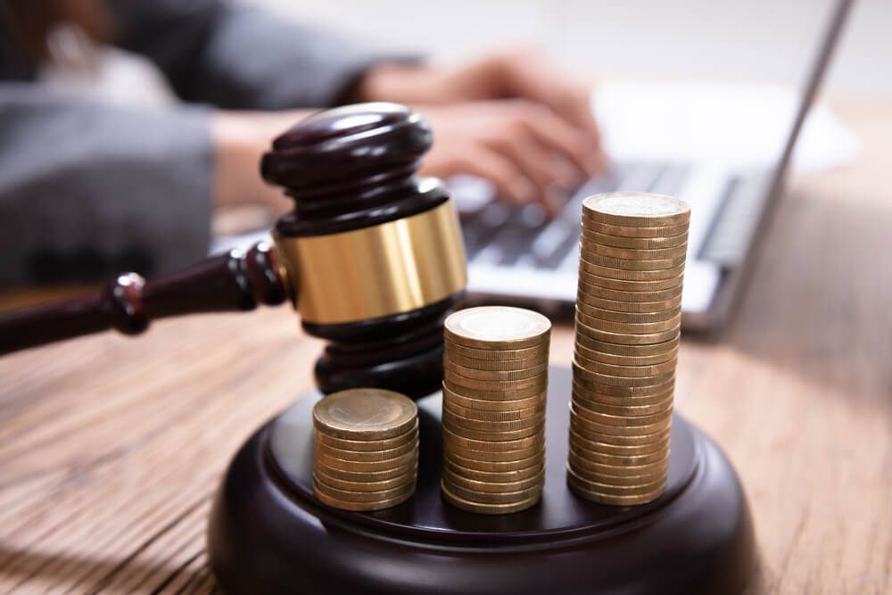 A judge 's gavel and stacks of coins on a wooden table.