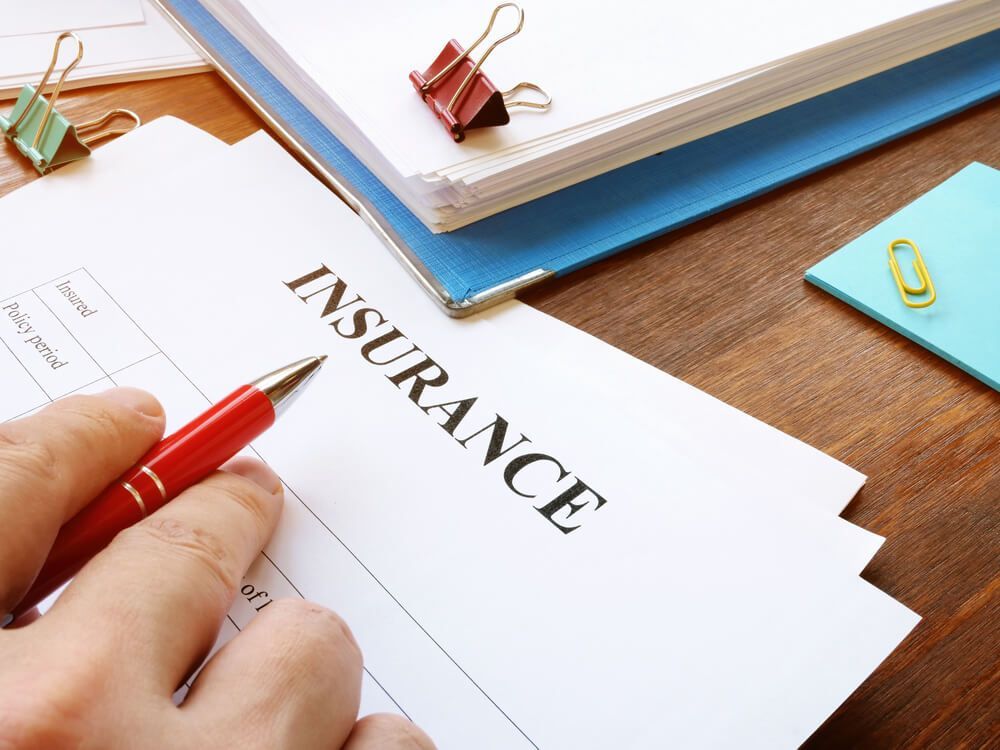 A person is filling out an insurance form with a pen