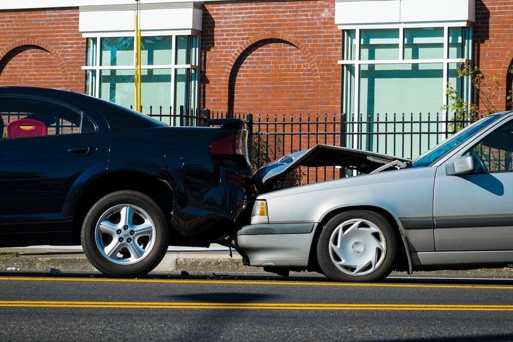 Two cars are involved in a car accident on the side of the road.