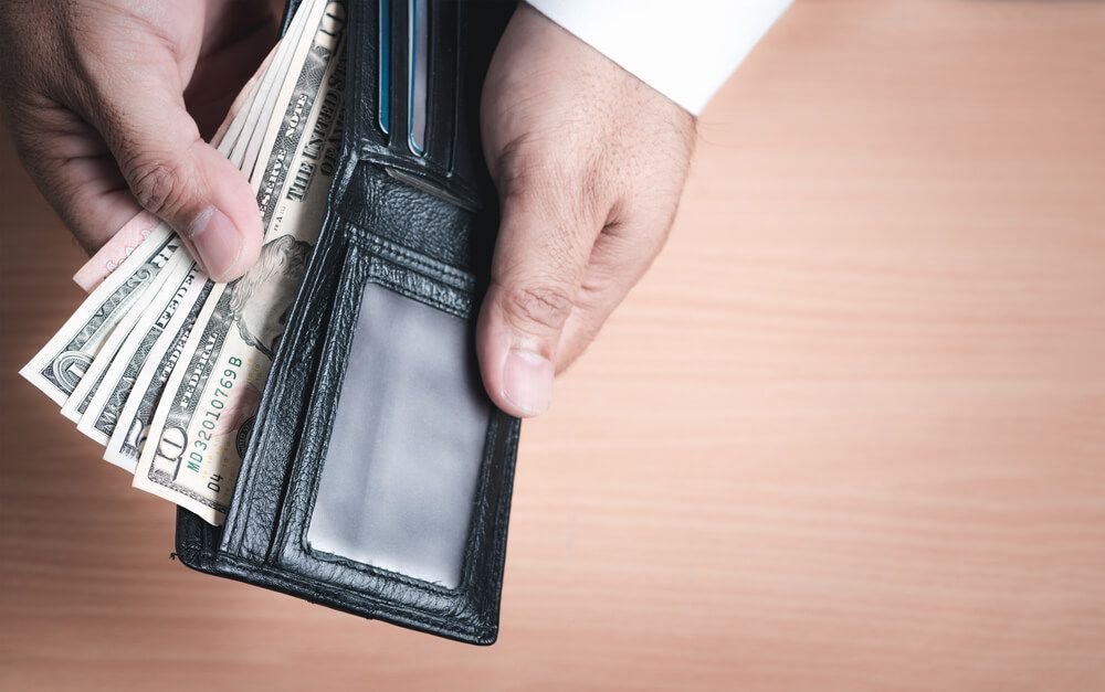 A man is taking money out of his wallet.