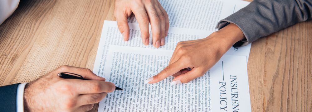 A man and a woman are sitting at a table signing a document.
