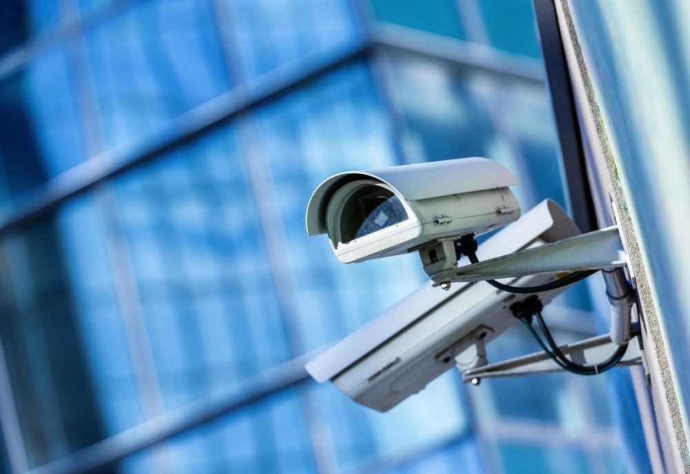 A security camera is mounted on a pole in front of a building.