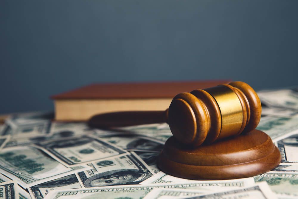 A wooden judge 's gavel is sitting on top of a pile of money.