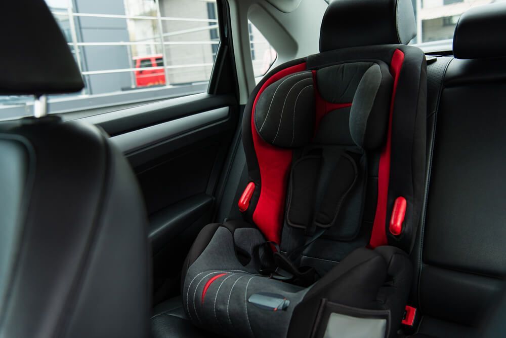 A red and black car seat is in the back seat of a car.