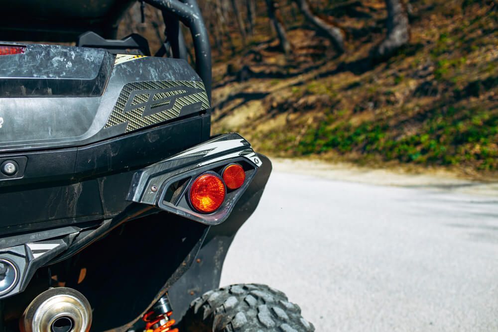 The back end of a atv is parked on the side of a road.