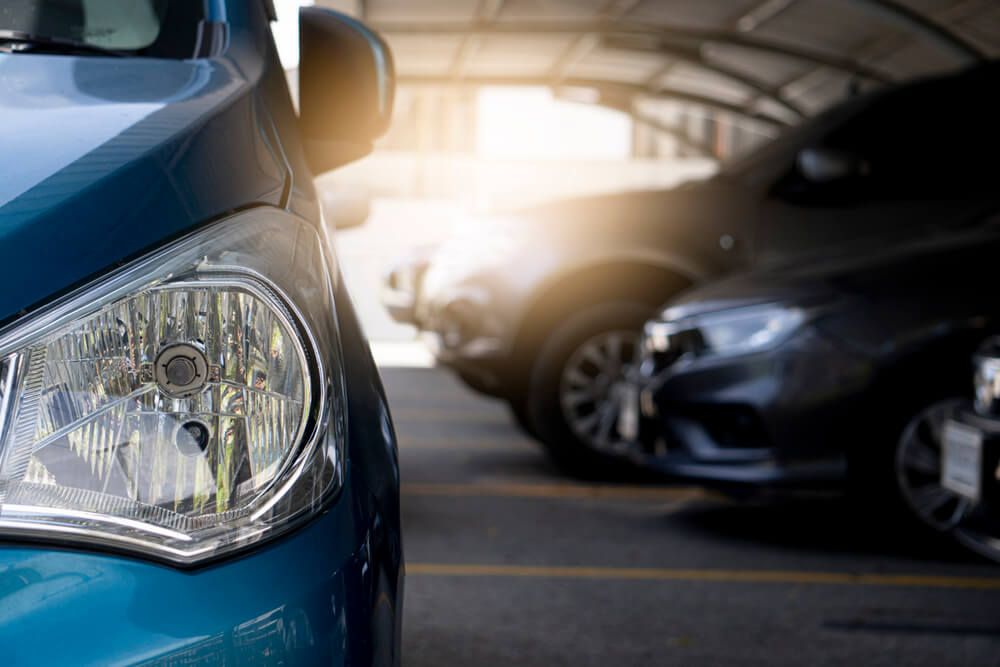 A close up of a car headlight in a parking lot.