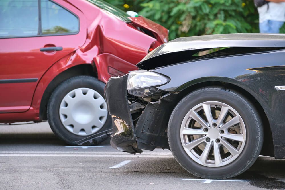 A red car and a black car are involved in a car accident.