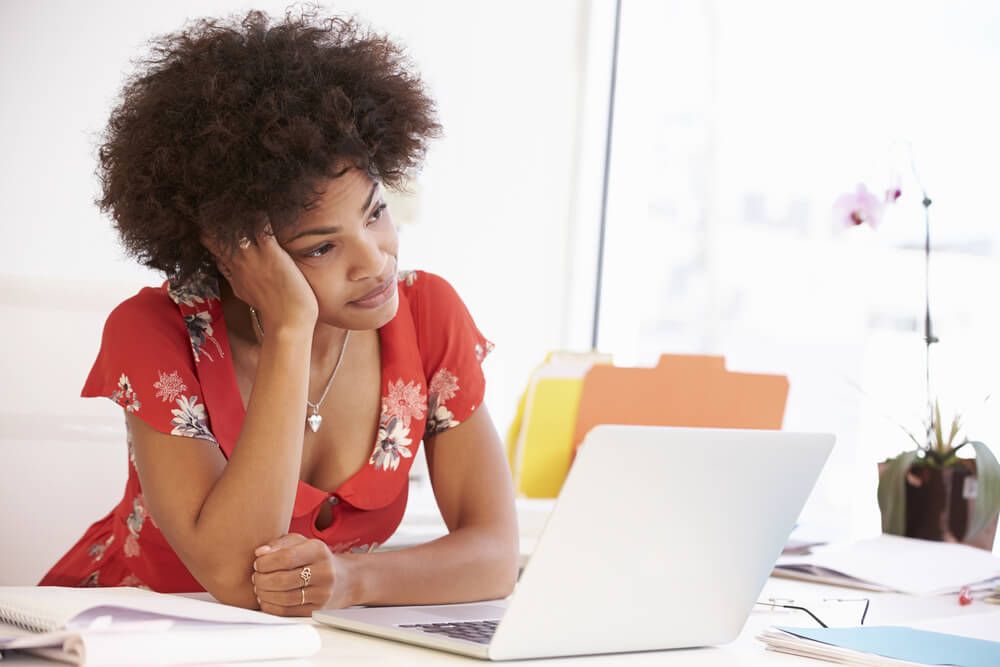 A woman is sitting at a desk using a laptop computer.