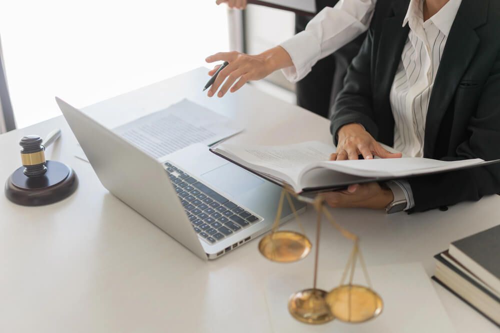A lawyer is sitting at a desk with a laptop and a book.
