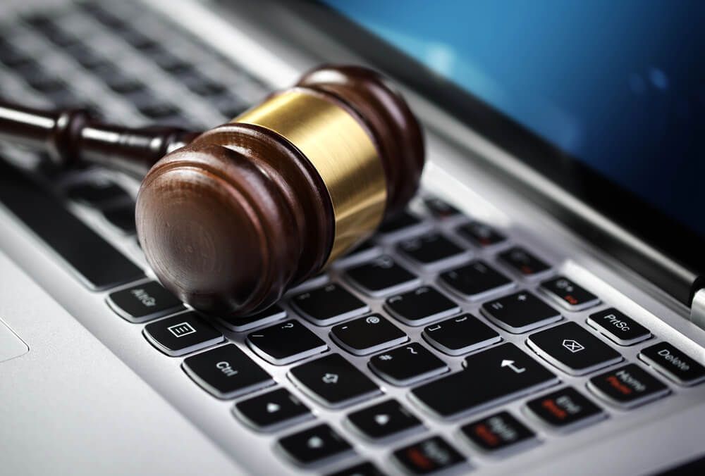 A wooden judge 's gavel rests on top of a laptop keyboard