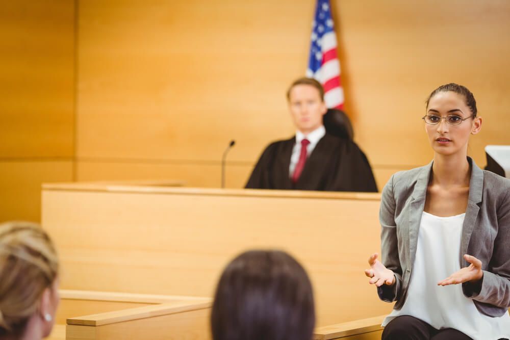 A woman is giving a speech in front of a group of people in a courtroom.