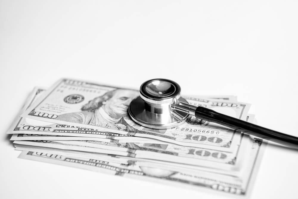 A stethoscope is sitting on top of a pile of money.