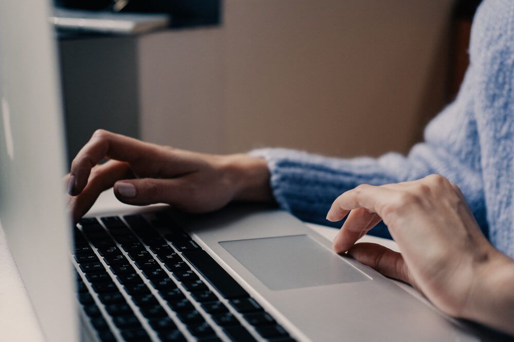 A woman is typing on a laptop computer.