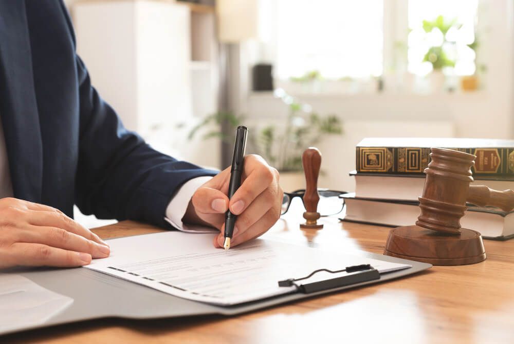 A man is writing on a piece of paper with a pen.