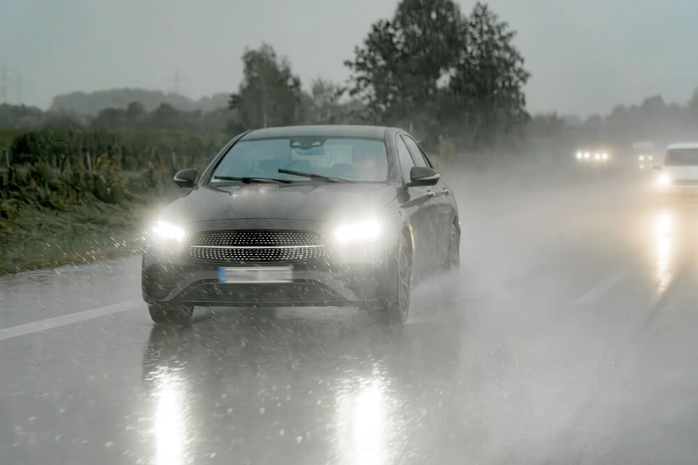 A car is driving down a wet road in the rain.