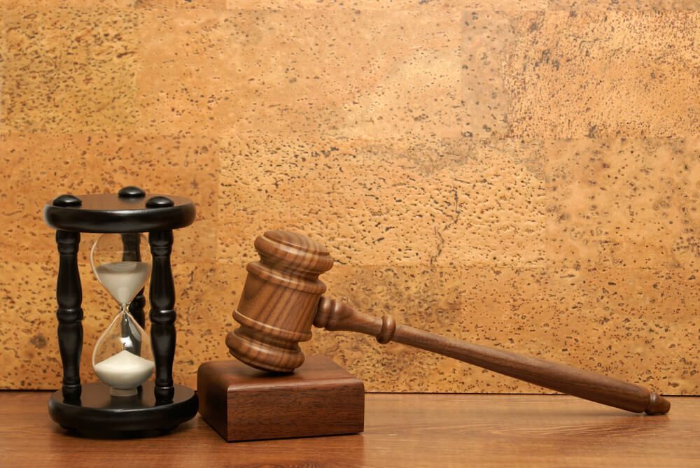 A wooden judge 's gavel and an hourglass on a wooden table