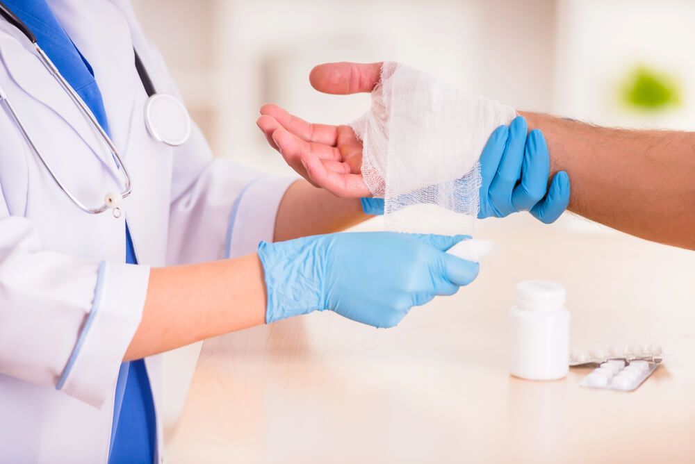 A doctor is bandaging a patient 's wrist with a bandage.