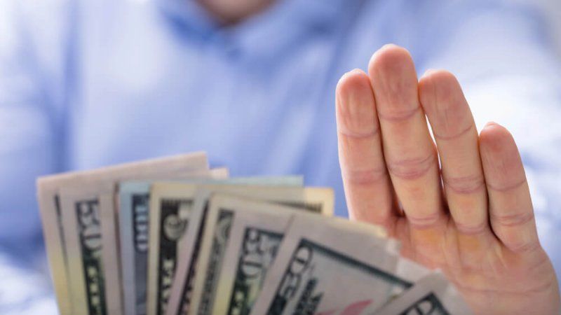 A person is holding a bunch of money in their hand.