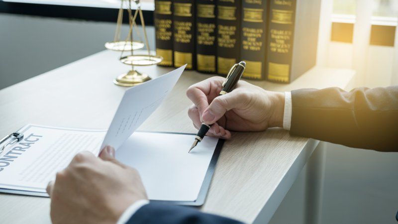 A man is writing on a piece of paper with a pen.
