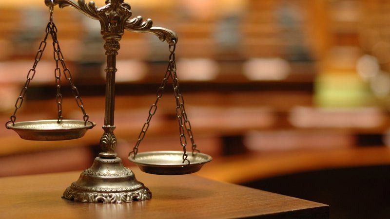 A scale of justice is sitting on a wooden table.