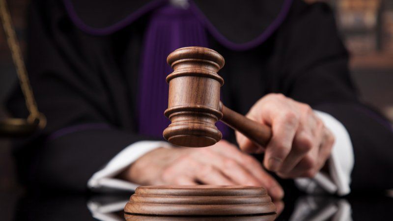 A judge is holding a wooden gavel in his hand.