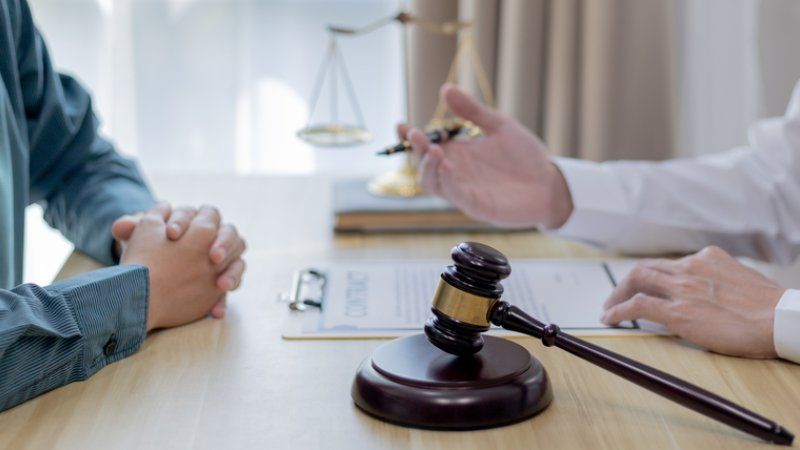 A man is sitting at a table with a judge 's gavel and a scale of justice.