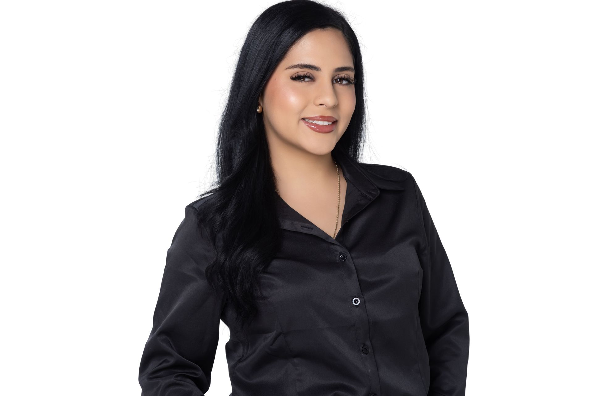A person with long dark hair, wearing a black collared button-down shirt, stands against a plain white background.