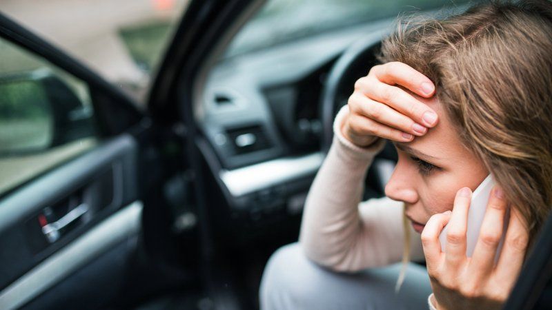 A woman is sitting in a car talking on a cell phone.