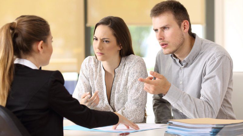A man and a woman are sitting at a table talking to a woman.
