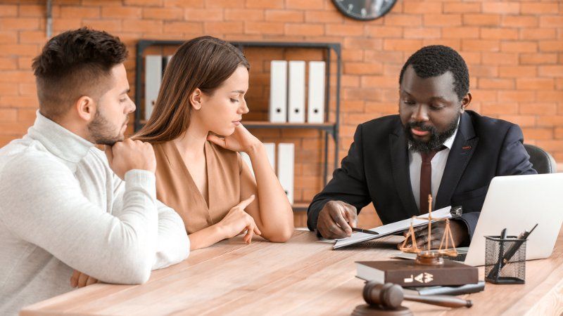 A man and a woman are sitting at a table talking to a lawyer.