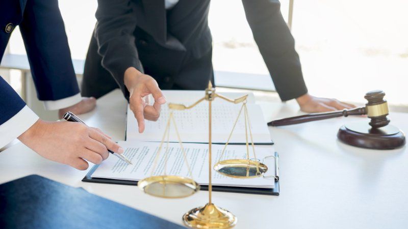 A group of lawyers are sitting at a table with scales of justice and a gavel.