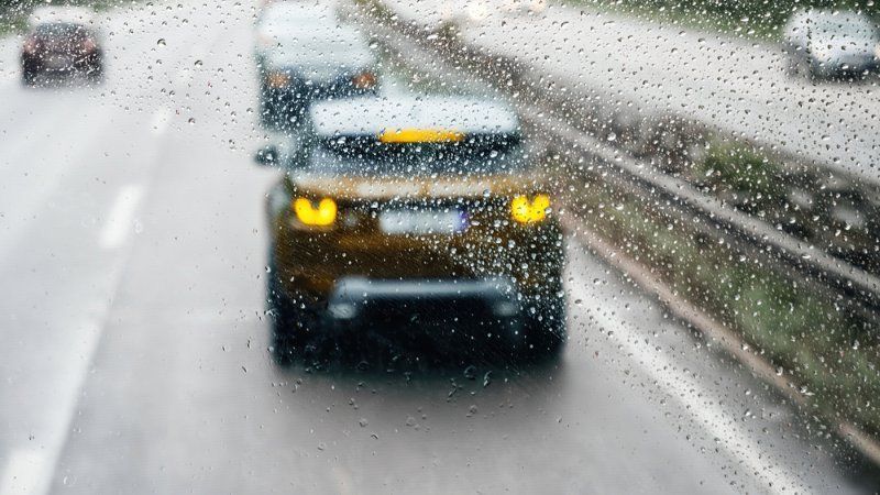 A car is driving down a highway in the rain.