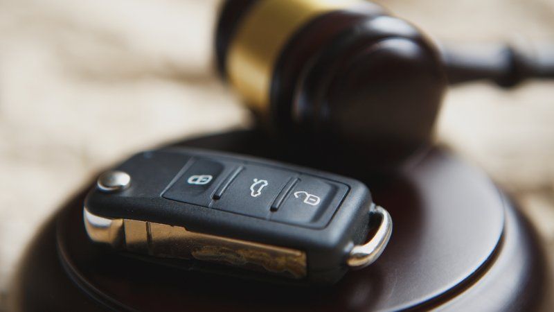 A car key is sitting on top of a wooden block next to a judge 's gavel.