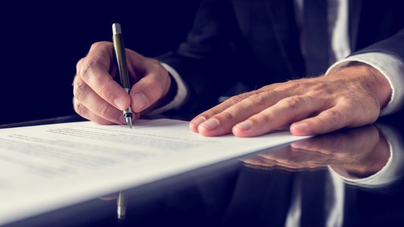 A man is writing on a piece of paper with a pen.