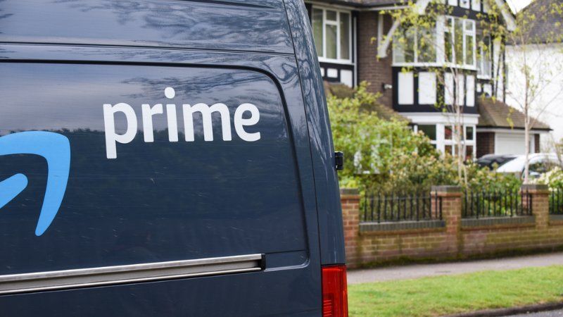 A black van with the word prime on the back is parked in front of a house.