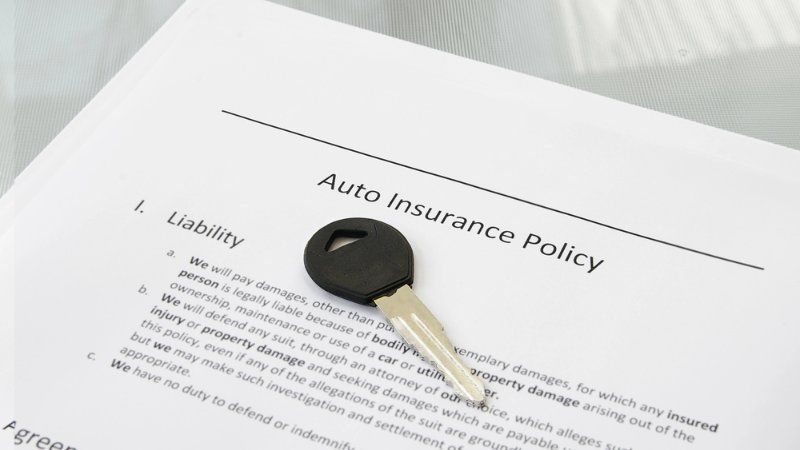 A car key lying on top of a printed auto insurance policy document.
