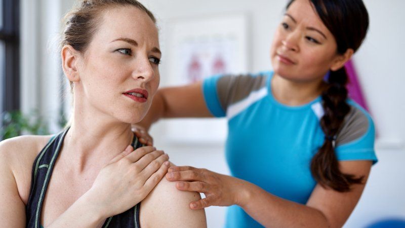 A woman is getting her shoulder examined by a doctor.