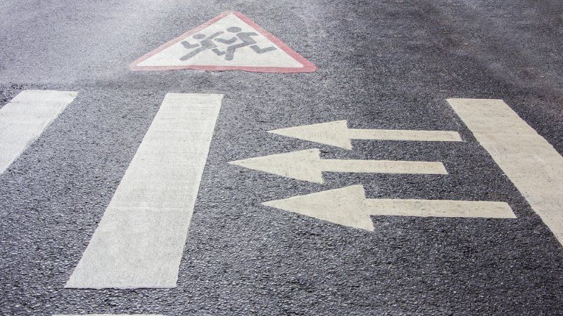 A close up of a crosswalk with arrows painted on it